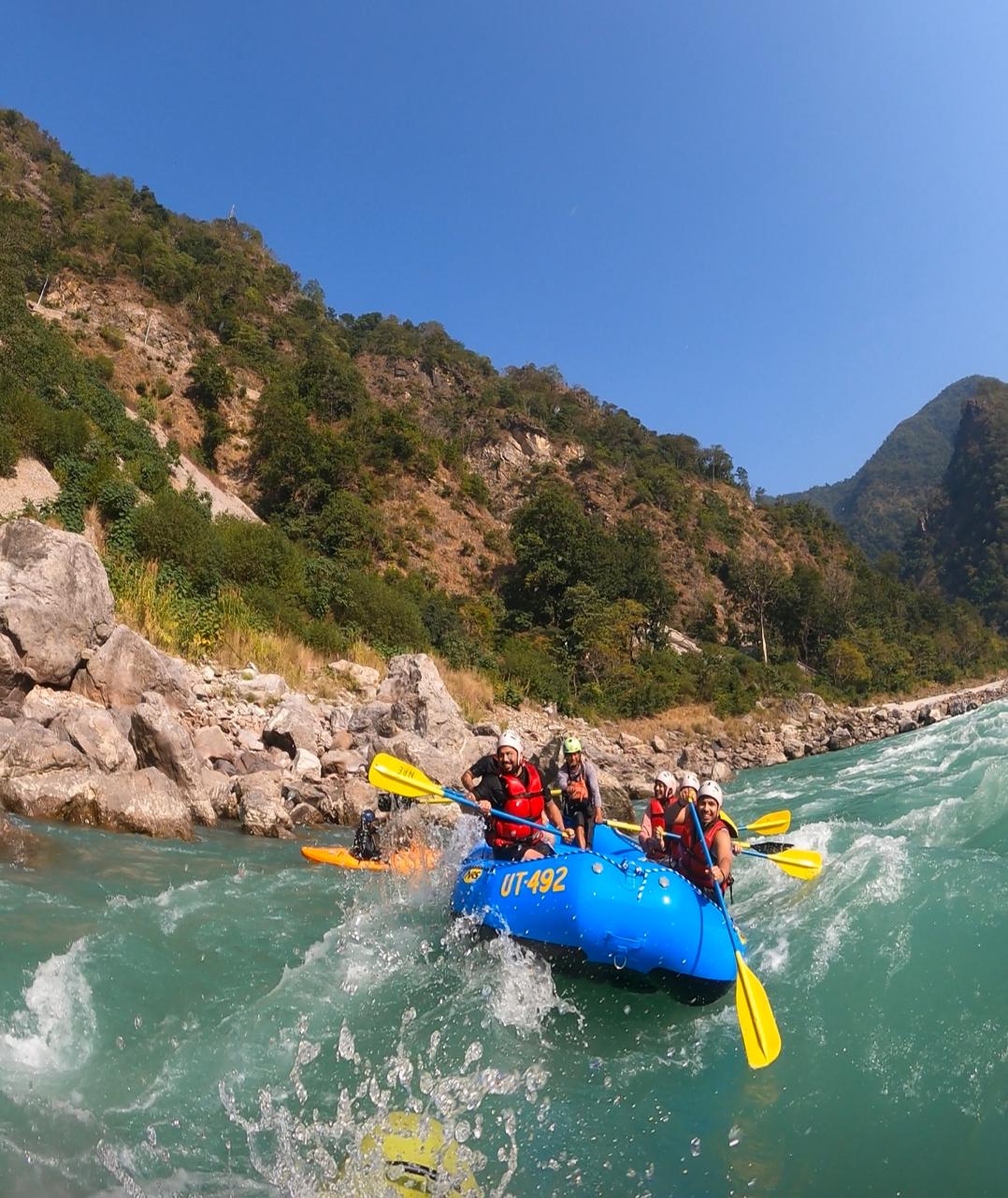 Group of happy people enjoying white water rafting in Rishikesh with Aquathrills Adventure